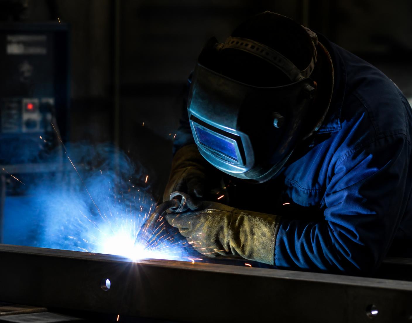Arapi Welding fabricator welding a steel beam with sparks and a bright welding arc